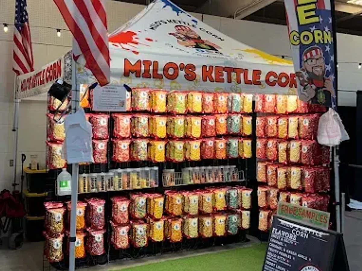 The Milo's Kettle Corn stand at a market: a red and white tent over a wall of popcorn bags in every color.